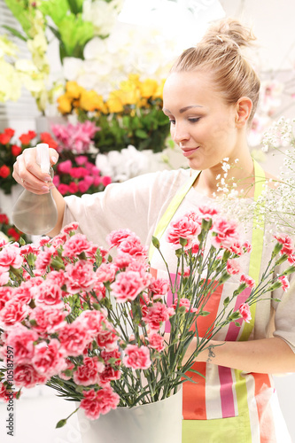 Spryskiwanie kwiatów.
Kwiaciarka pielęgnuje kwiaty w wazonie 