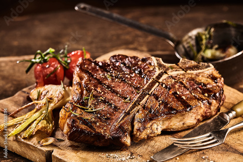Prepared grilled porterhouse steak with fork and knife photo