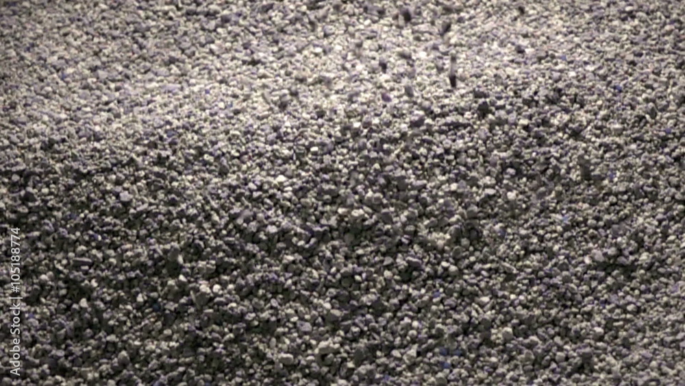 The granular cement crumb pours (filling of a cat's toilet tray), slow motion The granular cement crumb pours (filling of a cat's toilet tray), slow motion