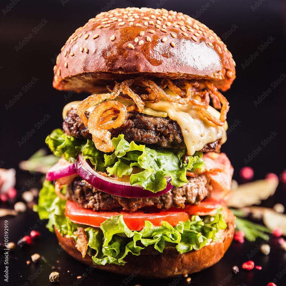 Foto Stock Juicy delicious burger with spices on a black background | Adobe  Stock