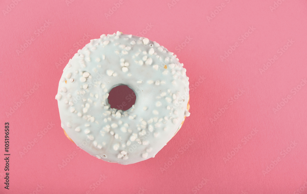Donut with blue glaze sprinkles on pink paper