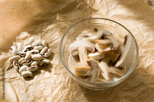 Белые грибы шампиньоны и свежие белые бобы на бумаге 