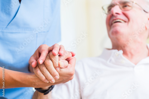 Altenpflegerin hält Hand von Senior in Altersheim