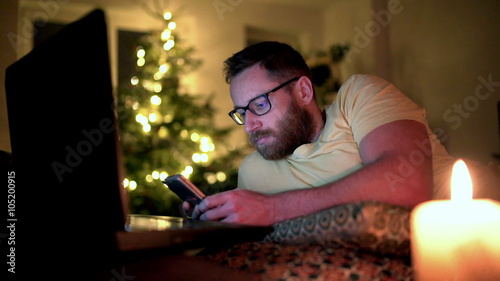 Happy man relaxing at home and texting on smartphone
 photo