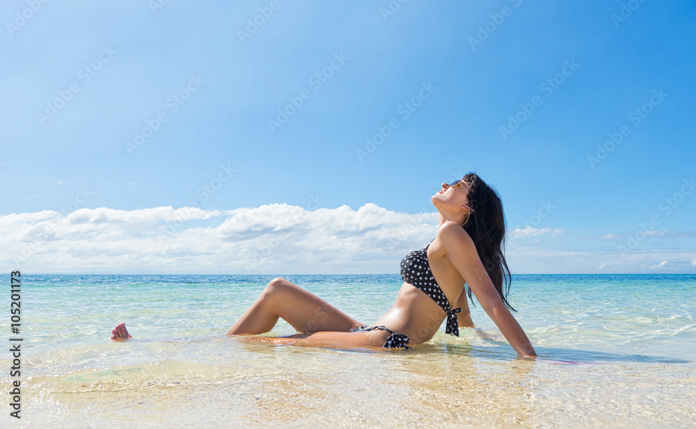 Young happy woman in black bikini enjoys sunny day on beach. Tropical vacation Young happy woman in black bikini enjoys sunny day on beach. Tropical vacation