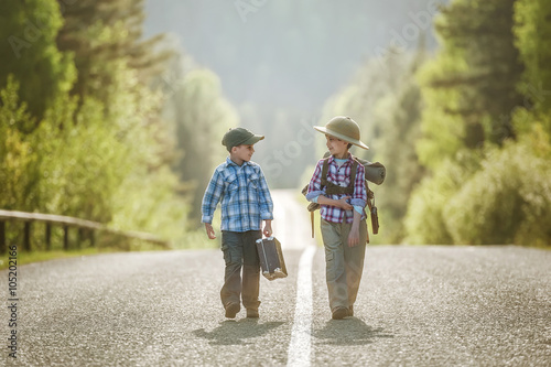 Boys travelers go on a mountain road in the sunset on a summer evening photo