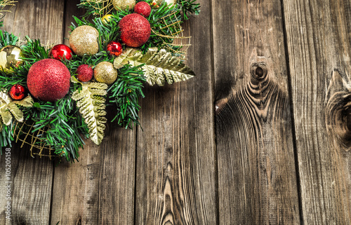 Christmas wreath on wooden door, decoration with ornaments on fir branches on rustic wood in brown