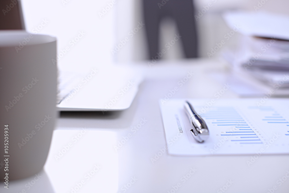 .Office workplace with a laptop and financial documents on the light reflecting table .Office workplace with a laptop and financial documents on the light reflecting table