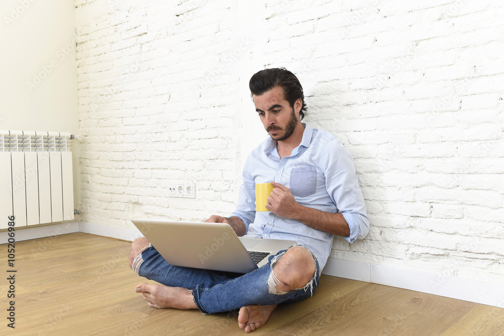 young man in hipster modern casual style look sitting on living room home floor working on laptop