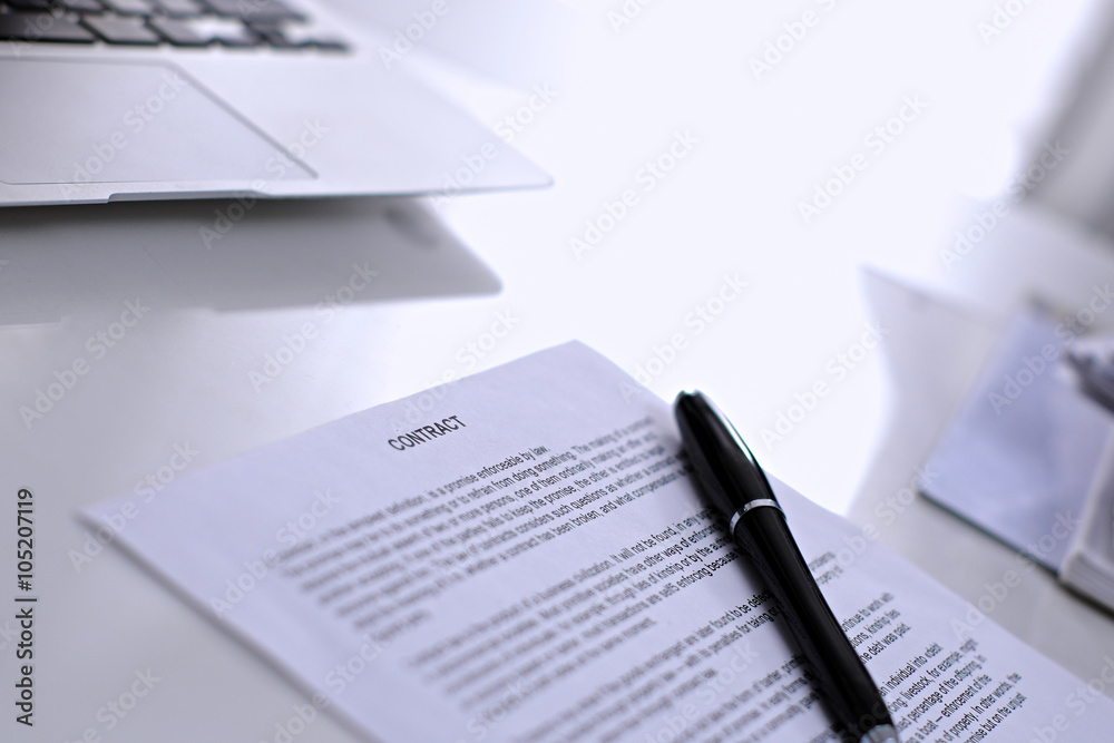 Obraz premium .Office workplace with a laptop and contract document on the light reflecting table