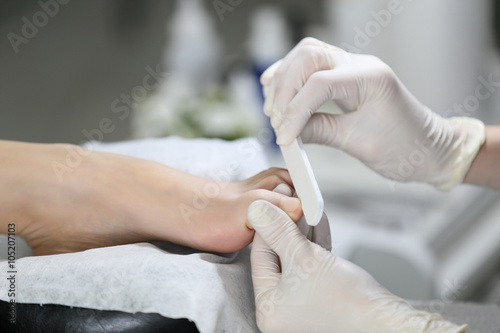 Close-up pedicure process of the big toe in spa salon. Professional work pedicure masters.