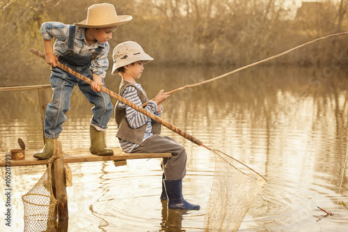 Boys fishes on a bridge on the lake photo