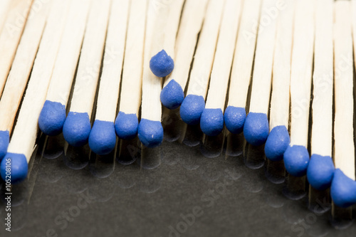 Unused matches with blue head screw on dark background photo