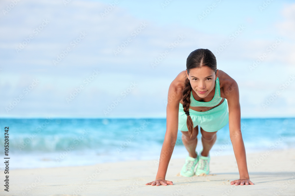 Fitness beach woman smiling planking doing yoga exercises. Happy Asian girl training her abs exercising her core muscles with the plank pose.