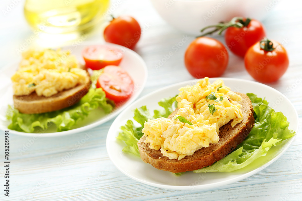 Scrambled eggs with bread and vegetables on a blue wooden table