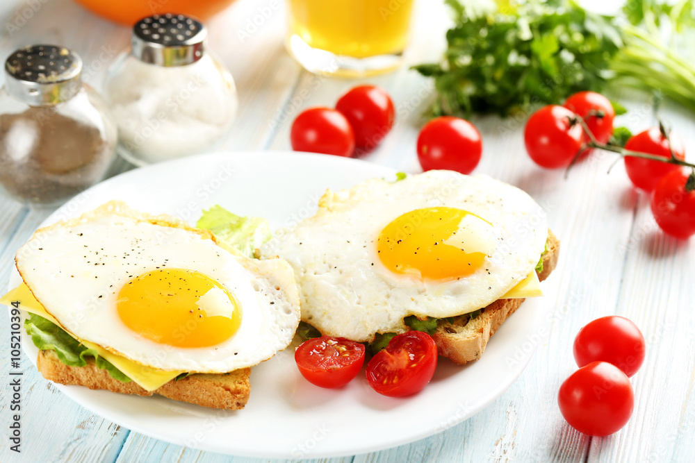 Fried eggs with toasts on plate on blue wooden table