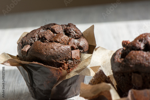 Chocolate muffins with icing and chocolate pieces.