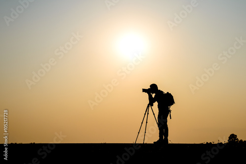Silhouette photographer in sunset background