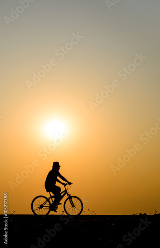 Silhouette of cyclist motion on sunset background