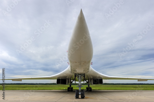 Bomber jet, supersonic military aircraft, white army plane, air force, modern aviation and aerospace industry, cloudy sky green grass and forest on background 