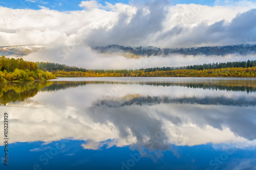 Autumn landscape with lake and mountain peaks in the background  