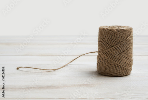 Spool of wool thread on a white wooden background. Top view desktop