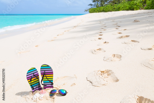 Fototapeta Naklejka Na Ścianę i Meble -  Multicolored flip-flops and sunglasses on a sunny beach..Tropica