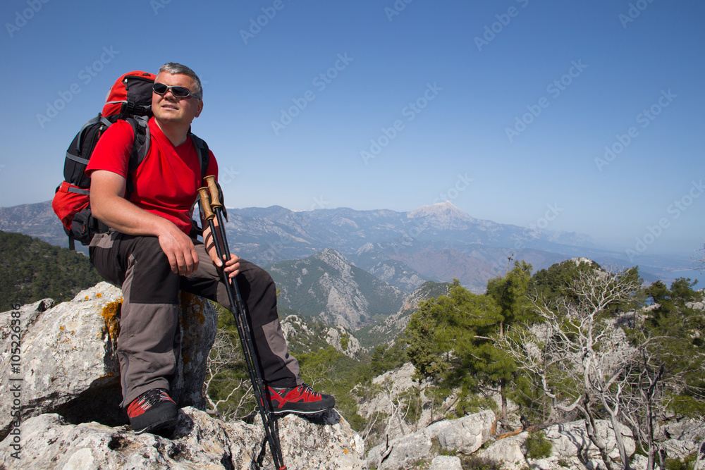 Hiker standing on top of the mountain with valley on the background.
