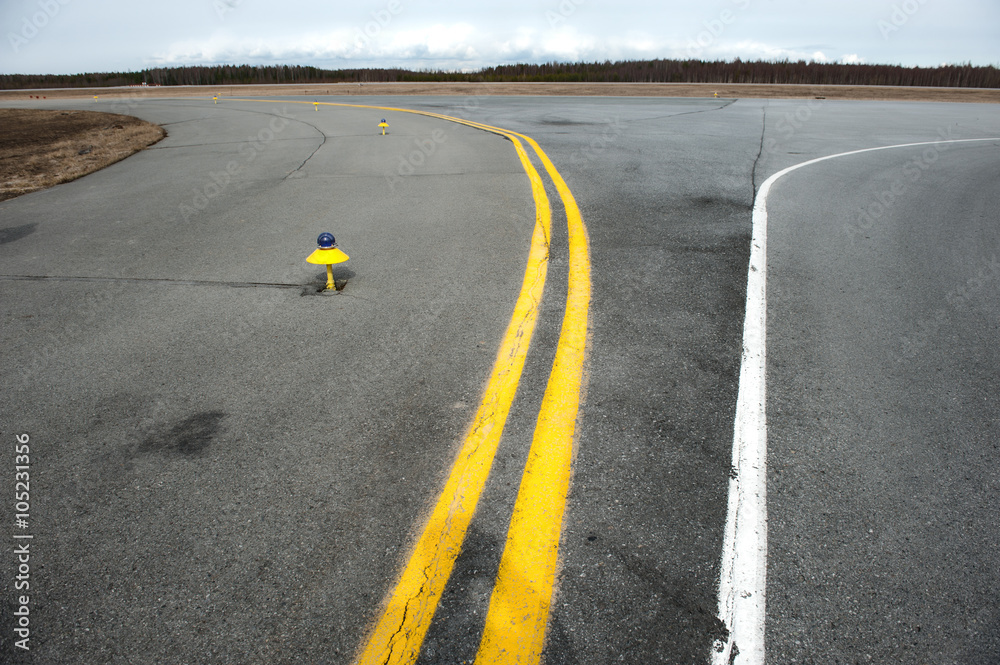 Yellow and white markings of a small airfield taxiway.