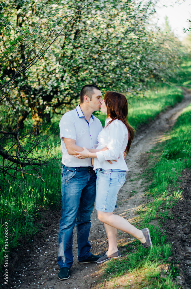 Happy pregnant couple kissing in booming garden Happy pregnant couple kissing in booming garden