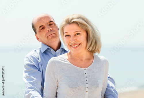 elderly couple standing hugging