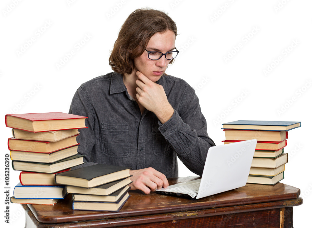 Young man sitting at a table with books and laptop