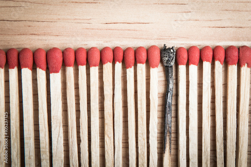 pile of match arrange in a row on a wood background and one of i