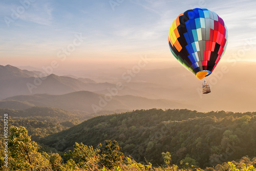 Colorful hot air balloon over mountain at sunset