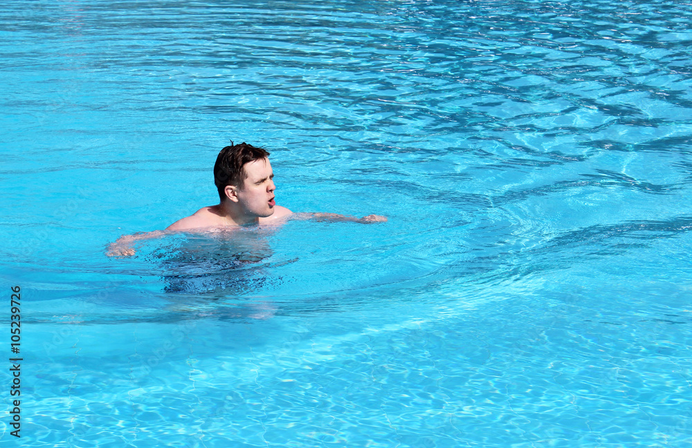 Young  emotional man swimming in the pool