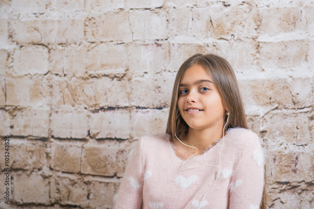 Portrait of teen girl with headphones on the brick wall background. beautiful girl in a sweater
Portrait of teen girl with headphones on the brick wall background. beautiful girl in a sweater