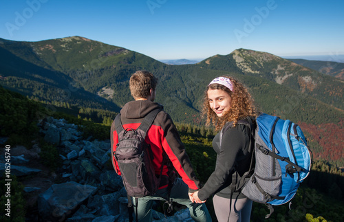Happy hiker couple walking in nature high in the mountains. Healthy lifestyle outdoors activity.