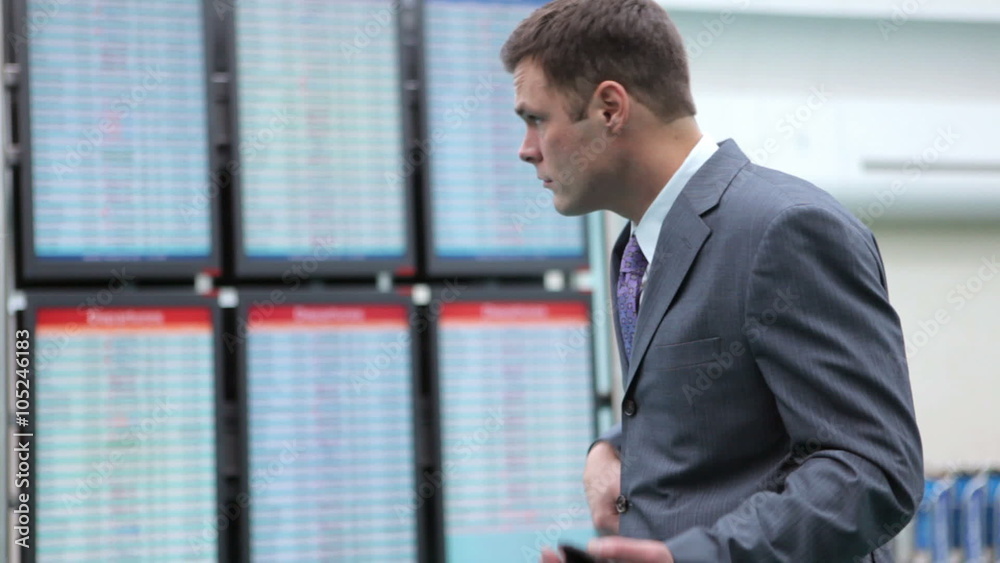 Business man at airport checks airline departure screens Business man at airport checks airline departure screens
