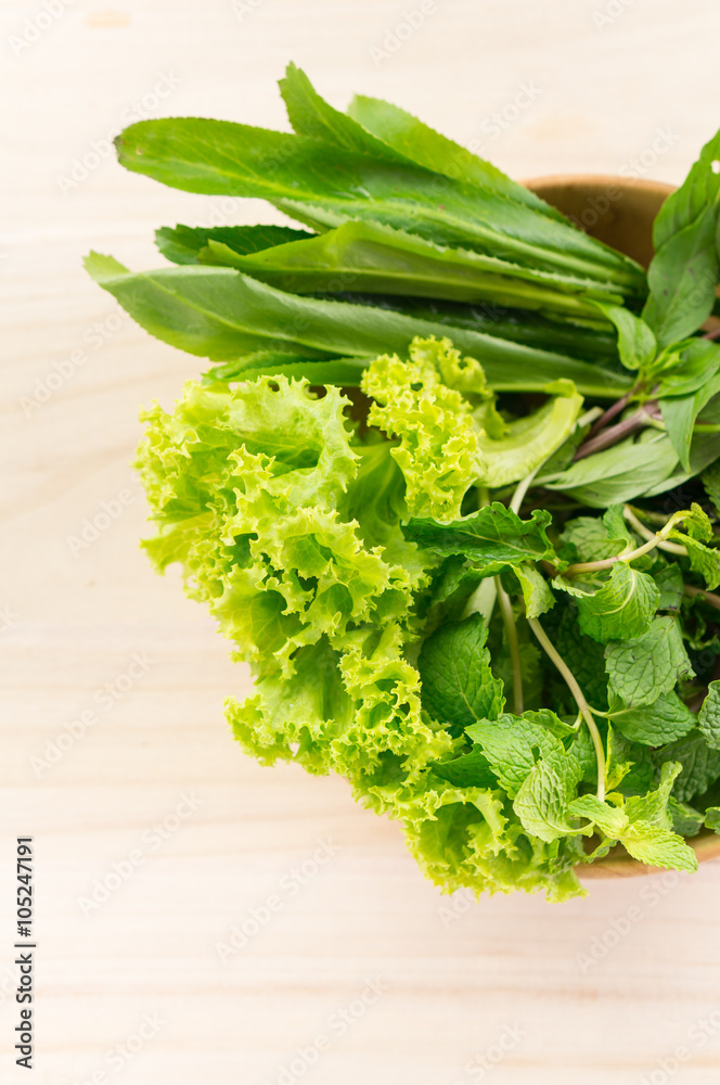 Green vegetables in wooden plate on wooden background Green vegetables in wooden plate on wooden background
