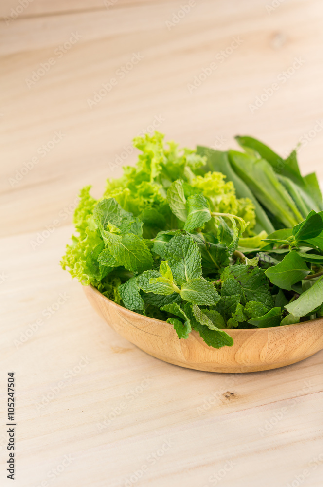 Green vegetables in wooden plate on wooden background Green vegetables in wooden plate on wooden background