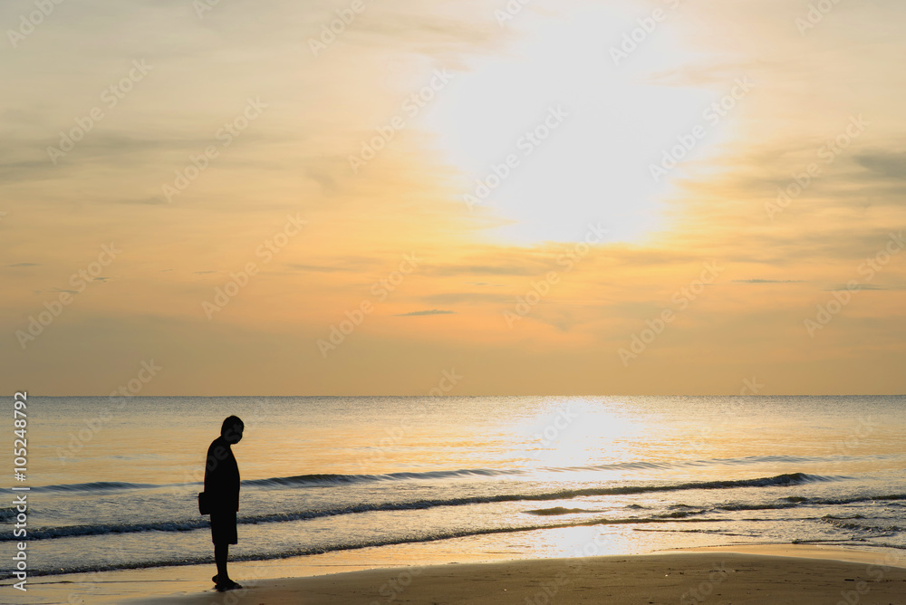 Man stand alone on the beach at sunset. Calm sea with waves.