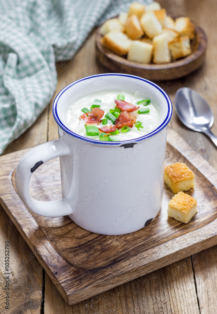 Creamy potato soup garnished with bacon and green onion, served in mug Creamy potato soup garnished with bacon and green onion, served in mug