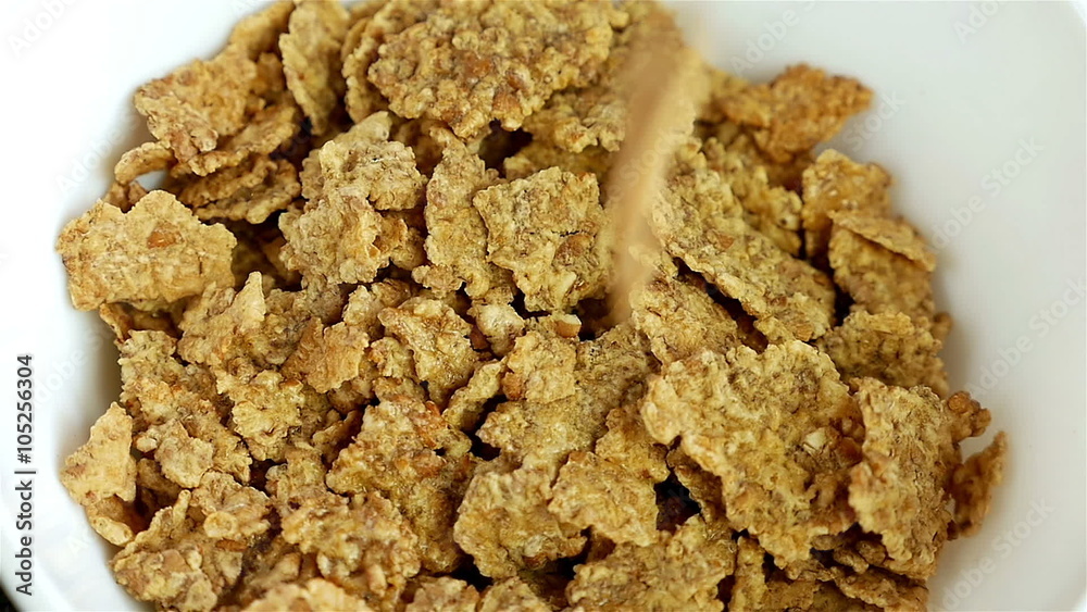 Cereal, dried cherries and hazelnuts are poured into a white breakfast bowl, slow motion Cereal, dried cherries and hazelnuts are poured into a white breakfast bowl, slow motion