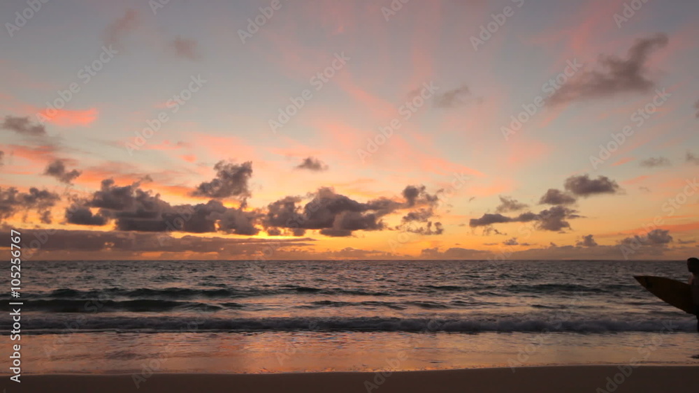 Surfer walking along beach at sunrise, Hawaii Surfer walking along beach at sunrise, Hawaii