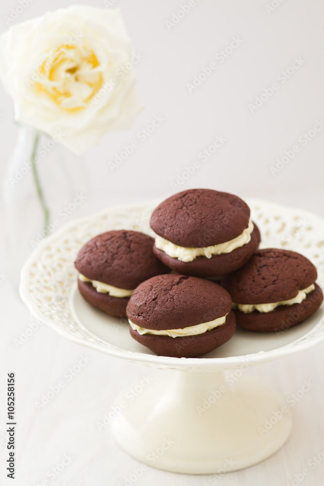 Chocolate whoopie pies with buttercream filling on cake stand