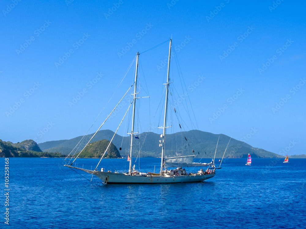 Sailboat navigates in the waters of the Archipelago of Les Saintes, Guadeloupe in the blue carribean sea.