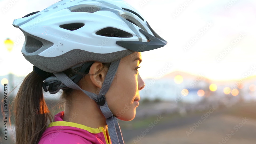 Young female cyclist wearing bike helmet looking at view during sunset. Beautiful woman with cycling helmet. enjoying nature while relaxing after biking. Young female cyclist wearing bike helmet looking at view during sunset. Beautiful woman with cycling helmet. enjoying nature while relaxing after biking.