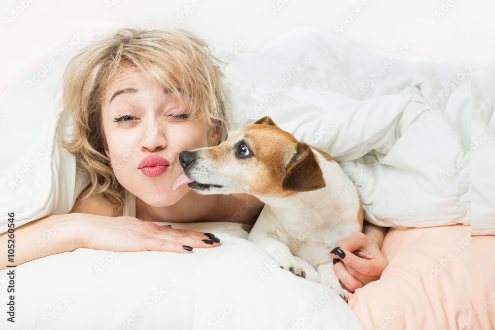 Happy funny morning mood. fooling around with pet on bed. Relaxed sleepy Woman and dog kiss on the pillow and linen Happy funny morning mood. fooling around with pet on bed. Relaxed sleepy Woman and dog kiss on the pillow and linen