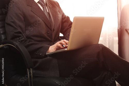 Business man sitting in chair and working on computer in his office while sunset shine to the window