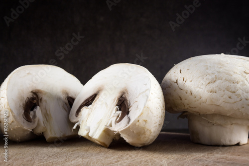 Champignon mushrooms on cutting board and dark background 